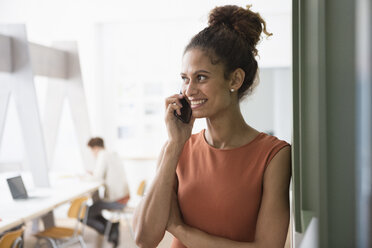 Lächelnde Frau im Büro am Mobiltelefon - RBF004948