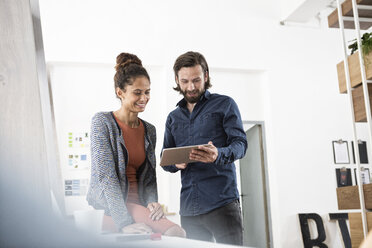 Two colleagues working together with digital tablet in office - RBF004962