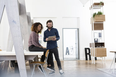 Zwei Kollegen arbeiten zusammen mit einem digitalen Tablet im Büro - RBF004972