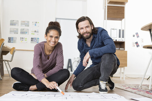 Porträt von zwei lächelnden Kollegen auf einer Büroetage mit Bauplan - RBF004974