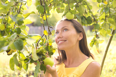 Smiling woman under an apple tree - KNTF000456