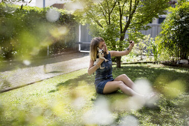 Frau macht Selfie mit ihrem Chihuahua im Garten - MAUF000821