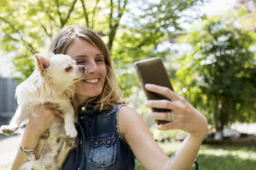 Woman taking selfie with her Chihuahua in the garden - MAUF000822