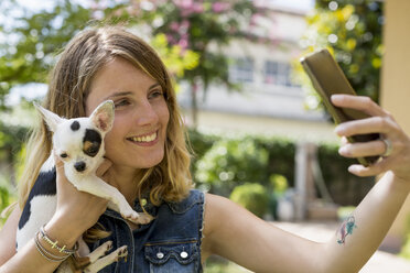 Frau macht Selfie mit ihrem Chihuahua im Garten - MAUF000823