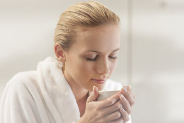 Young woman in bathrobe drinking tea - ZEF009603