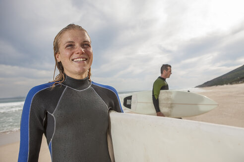 Lächelnde junge Frau mit Surfbrett am Strand - ZEF009631