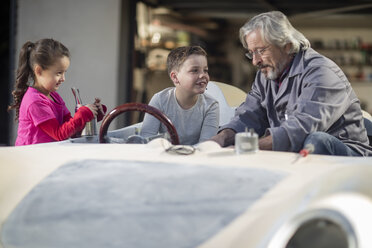 Älterer Mann mit Junge und Mädchen in einem zu restaurierenden Cabrio - ZEF009659