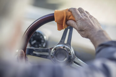 Älterer Mann beim Polieren des Lenkrads eines Autos - ZEF009665