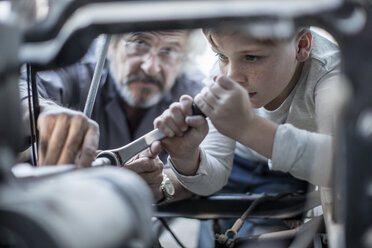 Senior man and boy working on mechanism of a car - ZEF009690