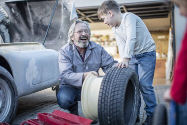 Happy senior man and boy changing car tire - ZEF009694