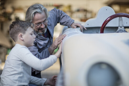 Senior man and boy examining old car together - ZEF009697