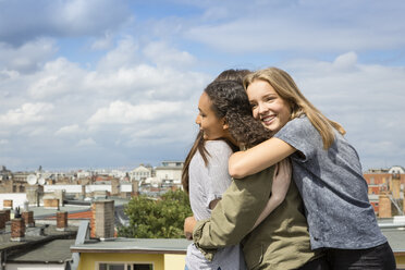 Drei glückliche Teenager-Mädchen umarmen sich auf dem Dach - OJF000150