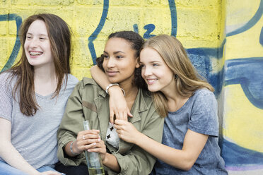 Three teenage girls sitting in front of graffiti - OJF000154