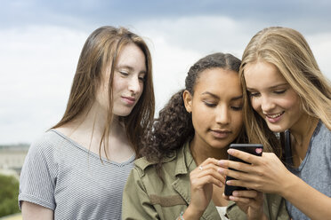 Drei Teenager-Mädchen auf dem Dach schauen auf ihr Handy - OJF000158