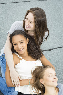 Drei Teenager-Mädchen entspannen sich zusammen auf dem Dach - OJF000165