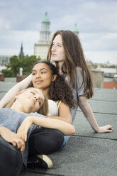Germany, Berlin, three teenage girls relaxing together on roof top - OJF000166