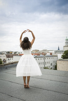 Deutschland, Berlin, Rückenansicht einer jungen Balletttänzerin beim Training auf einem Dach - OJF000170