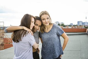 Deutschland, Berlin, drei Teenager-Mädchen stehen Arm in Arm auf einem Dach - OJF000177