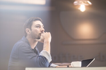 Man with digital tablet at office desk thinking - ZEF009702