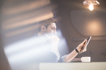 Man with digital tablet at office desk thinking - ZEF009703