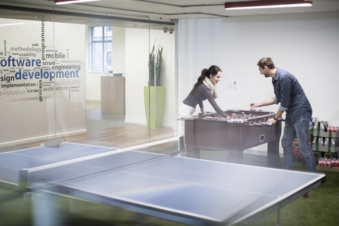 Two colleagues playing foosball in office break room - ZEF009706