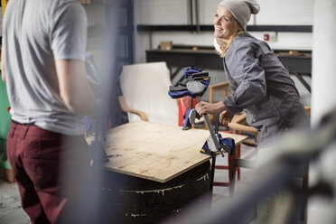 Smiling woman working on board in workshop - ZEF009757