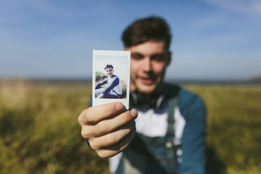 Junger Mann zeigt Polaroid von sich selbst - BOYF000538