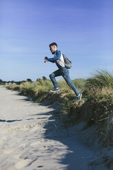 Junger Mann springt am Strand in die Luft - BOYF000547