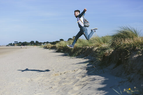 Junger Mann springt am Strand in die Luft - BOYF000549