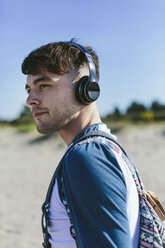Junger Mann mit drahtlosen Kopfhörern am Strand - BOYF000551