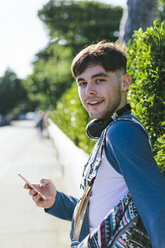 Porträt eines jungen Mannes mit Kopfhörern und Smartphone - BOYF000559