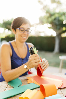 Woman doing handicrafts at garden table - JRFF000840