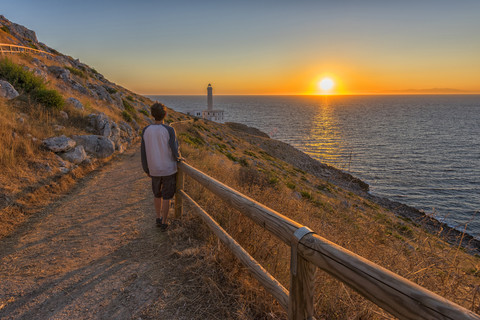 Italy, Apulia, Salento, Capo d'Otranto, man admiring the sunrise at lighthouse stock photo