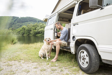 Man with dog in a van at lakeside - FMKF002781