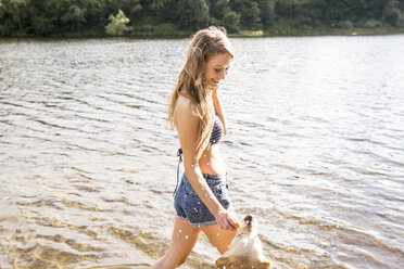 Junge Frau mit ihrem Hund in einem See - FMKF002800