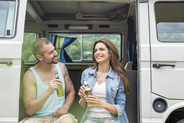 Lächelndes Paar mit Bierflaschen in einem Lieferwagen - FMKF002802