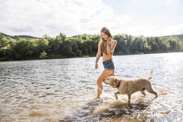 Young woman with her dog in a lake - FMKF002803