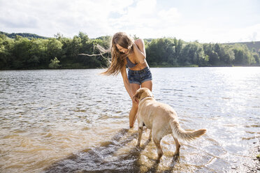Junge Frau mit ihrem Hund in einem See - FMKF002806
