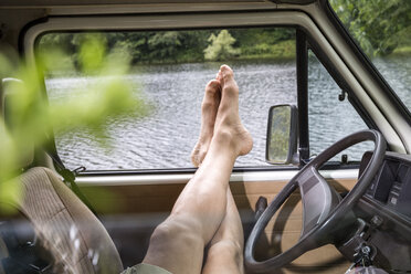 Beine eines Mannes, der sich in einem Lieferwagen am Seeufer entspannt - FMKF002811