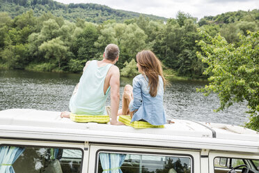 Pärchen auf dem Dach eines Lieferwagens am Seeufer - FMKF002825