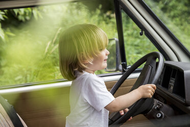 Toddler sitting at steering wheel of a van - FMKF002842
