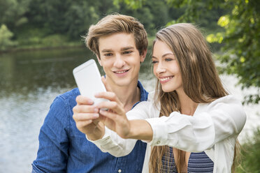 Young couple at lakeside taking a selfie - FMKF002874