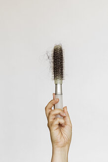 Hand holds a brush full of lost hair - MELF000139