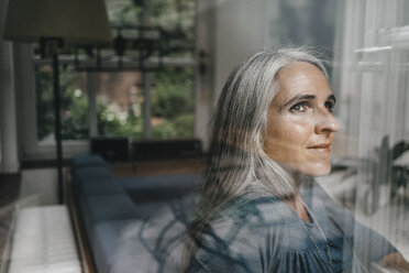 Woman at home looking through windowpane - KNSF000255