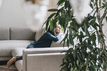 Woman sitting on the couch looking through window - KNSF000260