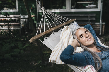 Woman relaxing in hammock in the garden - KNSF000283