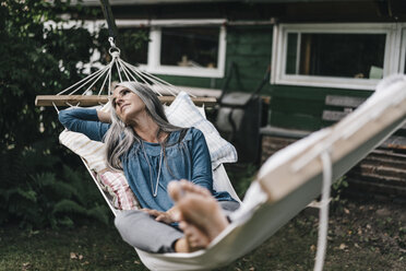 Pensive woman lying in hammock in the garden - KNSF000284