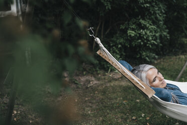 Woman relaxing in hammock in the garden - KNSF000286