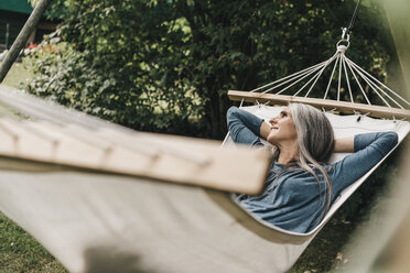 Woman relaxing in hammock in the garden - KNSF000288