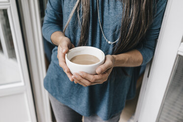 Woman's hands holding bowl of white coffee - KNSF000293